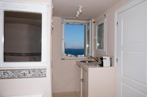 a white bathroom with a sink and a window at Marialena's studio in Agios Ioannis Mykonos