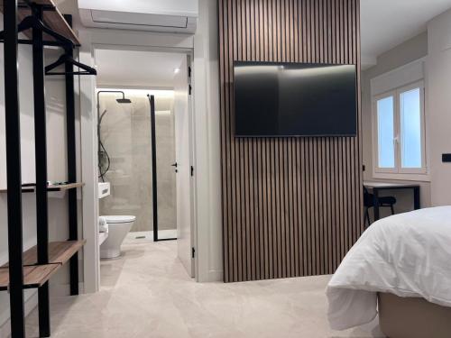 una camera da letto con TV a parete accanto a un bagno di TUEH TUDELA BALCON DE BARDENAS a Tudela