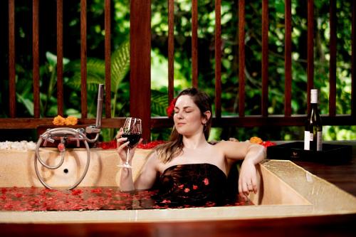 a woman in a bath tub holding a glass of wine at Nandini Jungle by Hanging Gardens in Payangan
