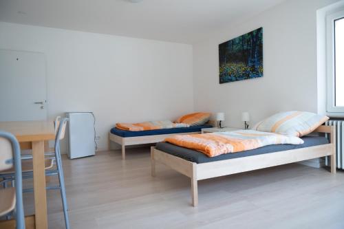 2 camas en una habitación con escritorio y mesa en Monteuerunterkunft - Flexibel und Modern!- NEU en Laichingen