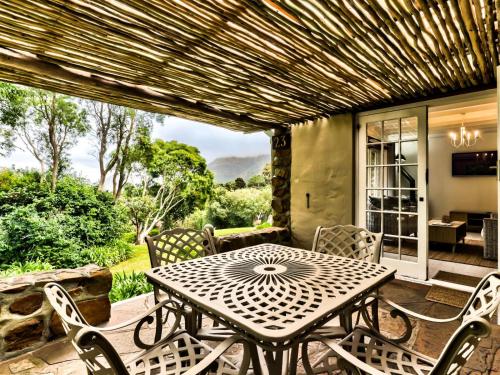 a wooden table and chairs on a patio with a table and chairs at Houtkapperspoort Mountain Cottages in Cape Town