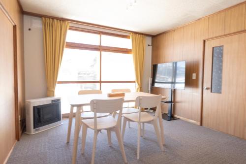 ein Esszimmer mit einem Tisch, Stühlen und einem TV in der Unterkunft +C FURANO in Furano