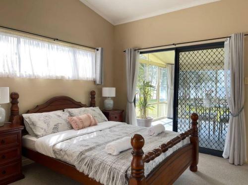 1 dormitorio con 1 cama y puerta corredera de cristal en Aircabin - Tuggerawong - Lake Front - 3 Beds House, en Rocky Point