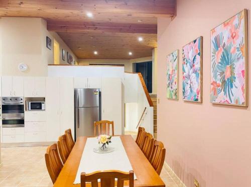 een keuken met een tafel met stoelen en een koelkast bij Aircabin - Tuggerawong - Lake Front - 3 Beds House in Rocky Point