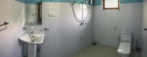 a white bathroom with a sink and a toilet at Sigiriya Rock Star Home Stay in Sigiriya