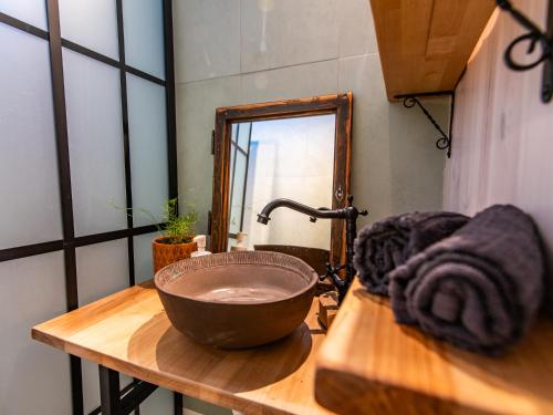 a bathroom with a bowl sink and a mirror at Minifaktúra Loft Apartman & Reggeliző és Ételbár in Szokolya