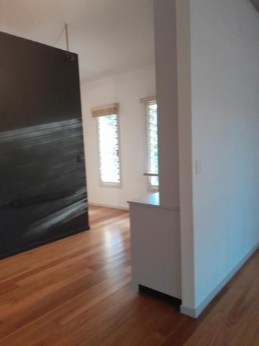 una sala de estar vacía con puerta negra y suelo de madera en Bitolovo, en Nimbin