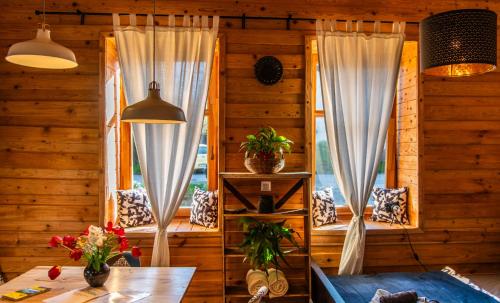 a room with two windows with curtains and a table at Minifaktúra Loft Apartman & Reggeliző és Ételbár in Szokolya