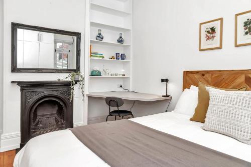Schlafzimmer mit einem Bett, einem Schreibtisch und einem Kamin in der Unterkunft 'The Cosy Corner' Classic Haven with Modern Comforts in Adelaide