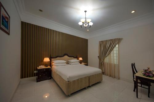 een slaapkamer met een bed, een tafel en een kroonluchter bij Royal Residence Hotel Apartments in Umm Al Quwain