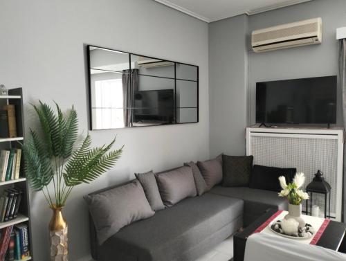 a living room with a gray couch and a mirror at NikhsHome in Loutraki