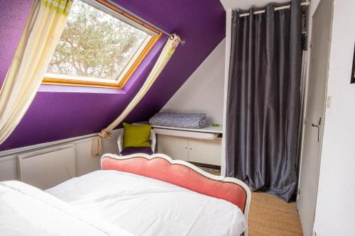 カミエにあるBienvenue à Sainte Cécile Plageの紫の壁のベッドルーム1室、窓付きのベッド1台が備わります。