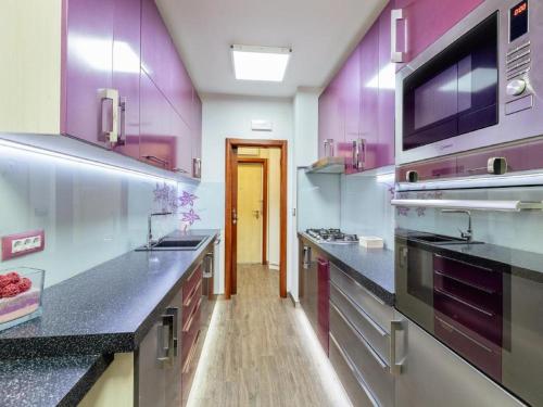 una cocina con paredes púrpuras y electrodomésticos de acero inoxidable en Apartment Petit Jolie, en Herceg-Novi