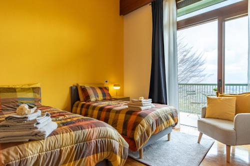 Duas camas num quarto com paredes amarelas e uma janela em Al Castagneto Foresteria Lombarda em Montevecchia