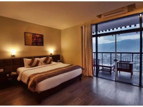 a bedroom with a large bed and a large window at Tara valley view in Gangtok