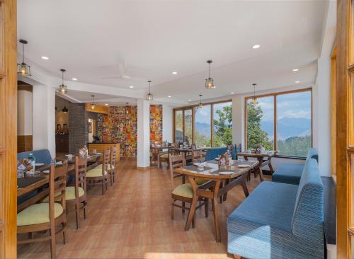 a restaurant with tables and chairs and windows at Zone Connect by The Park Mussoorie in Mussoorie