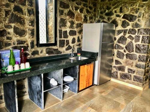 a stone kitchen with a sink and a refrigerator at Enliven Homestay Alibag, Alibaug in Nagaon