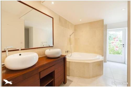 bagno con lavandino, vasca e specchio di MAS # PISCINE OLIVERAIE RUISSEAU CHEVAUX # SALAGOU a Lacoste
