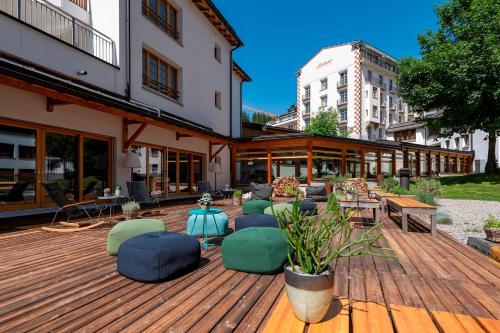 una terraza de madera con sillas y mesas en un edificio en Hotel Schweizerhof Lenzerheide en Lenzerheide