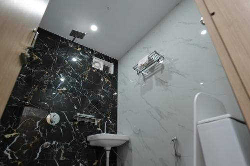 baño con pared de mármol blanco y negro en INDRALOK INN., en Hazārībāg