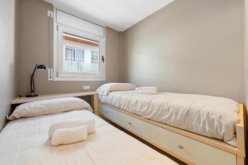 a bedroom with two beds and a window at Hauzify I Apartaments La Martina in Torredembarra