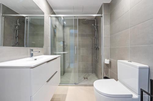 a bathroom with a shower and a toilet and a sink at Hauzify I Apartaments La Martina in Torredembarra
