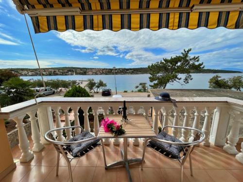 a table and chairs on a balcony with a view of the water at Villa Tiha Lili in Šilo