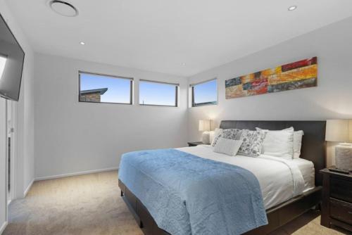 a white bedroom with a bed and some windows at Stunning Luxe Home Near Airport in Auckland