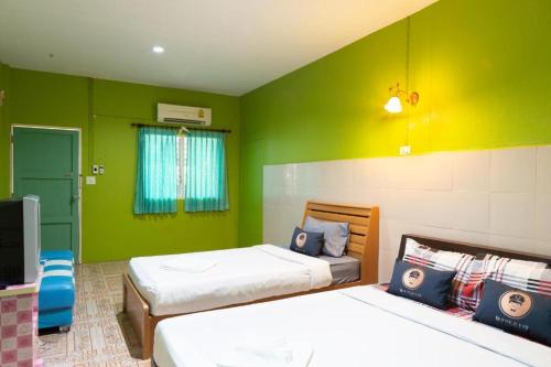 two beds in a room with green walls at RoomQuest Amphawa Vaylasamran in Amphawa
