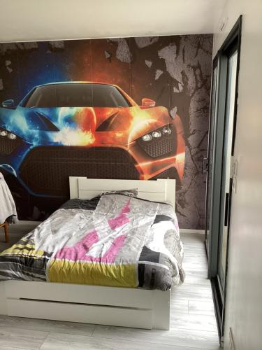 1 dormitorio con 1 cama y un mural de coche en Maison 24h du Mans et jeux olympiques, en Moncé-en-Belin