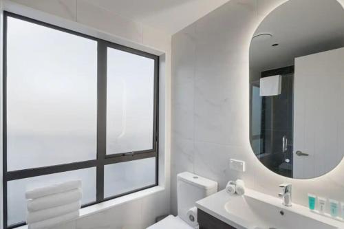 La salle de bains est pourvue d'un lavabo, d'un miroir et d'une fenêtre. dans l'établissement Stunning Luxe Home Near Airport, à Auckland