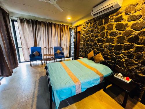 a bedroom with a bed and a stone wall at Enliven Homestay Alibag, Alibaug in Nagaon
