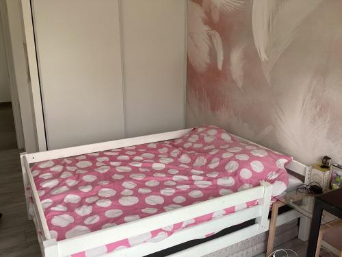 1 cama pequeña con sábanas de lunares rosas y blancas en Maison 24h du Mans et jeux olympiques, en Moncé-en-Belin