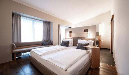a hotel room with a large bed and a window at HAIDVOGL MAVIDA Zell am See in Zell am See