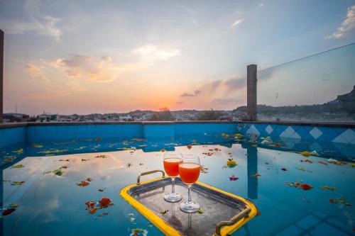 two glasses of wine sitting on top of a swimming pool at Amritara Manak Haveli, Jodhpur in Jodhpur
