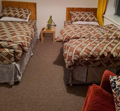 a bedroom with two beds and a table with a lamp at Double rooms available, near Safari Park & Hospital in Franche