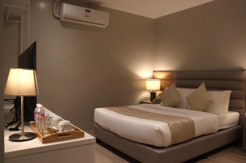 - une chambre avec un lit, une télévision et des lampes dans l'établissement Caliraya Mountain Lake Resort, à Cavinti