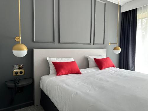 a bedroom with a white bed with two red pillows at Hôtel Spa Du Béryl in Bagnoles de l'Orne