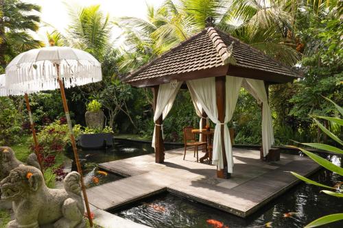 a gazebo in a garden with a koi at Adiwana Unagi Suites in Ubud