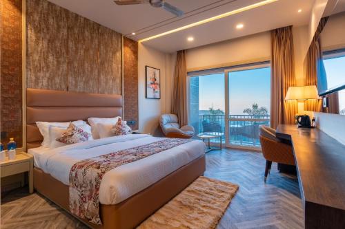 a hotel room with a bed and a desk and a window at Mountoria Retreat Bhimtal- by Leisure Hotels Group in Bhīm Tāl