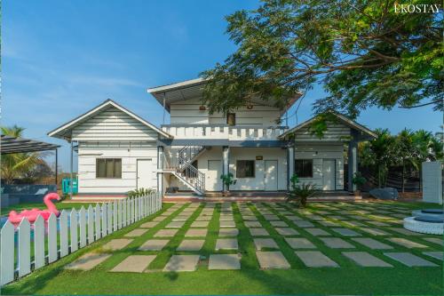 uma casa branca com uma cerca branca em EKO STAY- Lakefront Villa em Alibaug