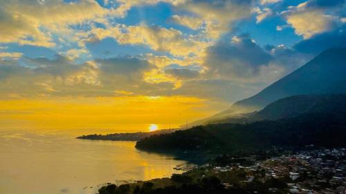 a sunset over the water with a city and mountains at Casa Mendoza Santiago Atitlan in Sololá