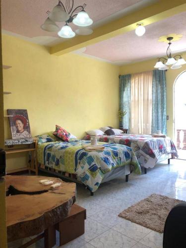 a living room with two beds and a table at Casa Mendoza Santiago Atitlan in Sololá