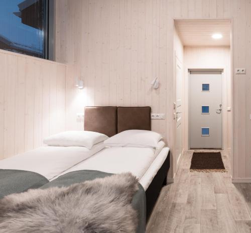 a bedroom with a bed with white sheets and a rug at Tromsø Lodge & Camping in Tromsø