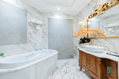 a bathroom with a tub and a sink and a mirror at Luxe Paradise Suite Hotel Trich Sai in Hanoi