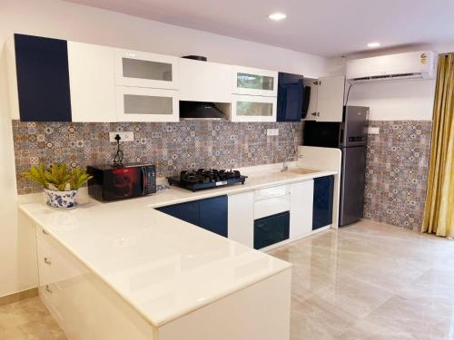 a kitchen with white cabinets and a black refrigerator at Villa Amarela in Panaji