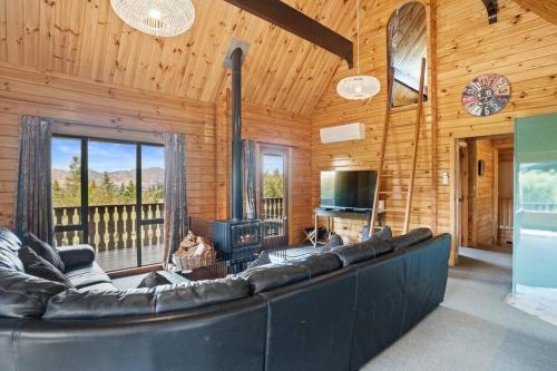 a living room with a black couch and a television at Welcome to the “Mountain Gem”! in Hanmer Springs