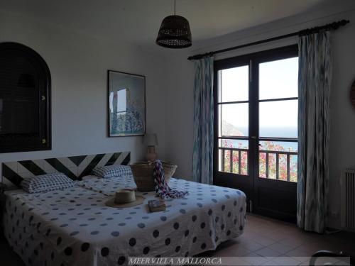 1 dormitorio con cama y ventana grande en Meervilla Mallorca - Charmantes Ferienhaus mit phantastischem Meerblick in Canyamel, en Canyamel