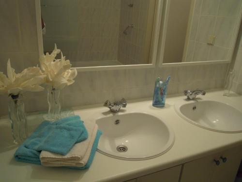 a bathroom counter with a sink and a vase of flowers at Appartement Seabird in Zandvoort