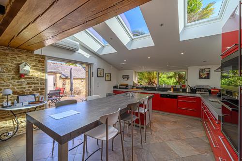 une cuisine avec une grande table et quelques fenêtres dans l'établissement TY ELISTHER - Maison de charme à Saint-Colombier, à Sarzeau